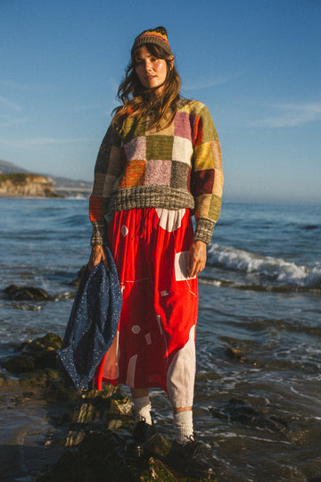 The Christmas Skirt, a vibrant red skirt features bold white patches and intricate appliqué needlework, combining comfort and style in a standout design