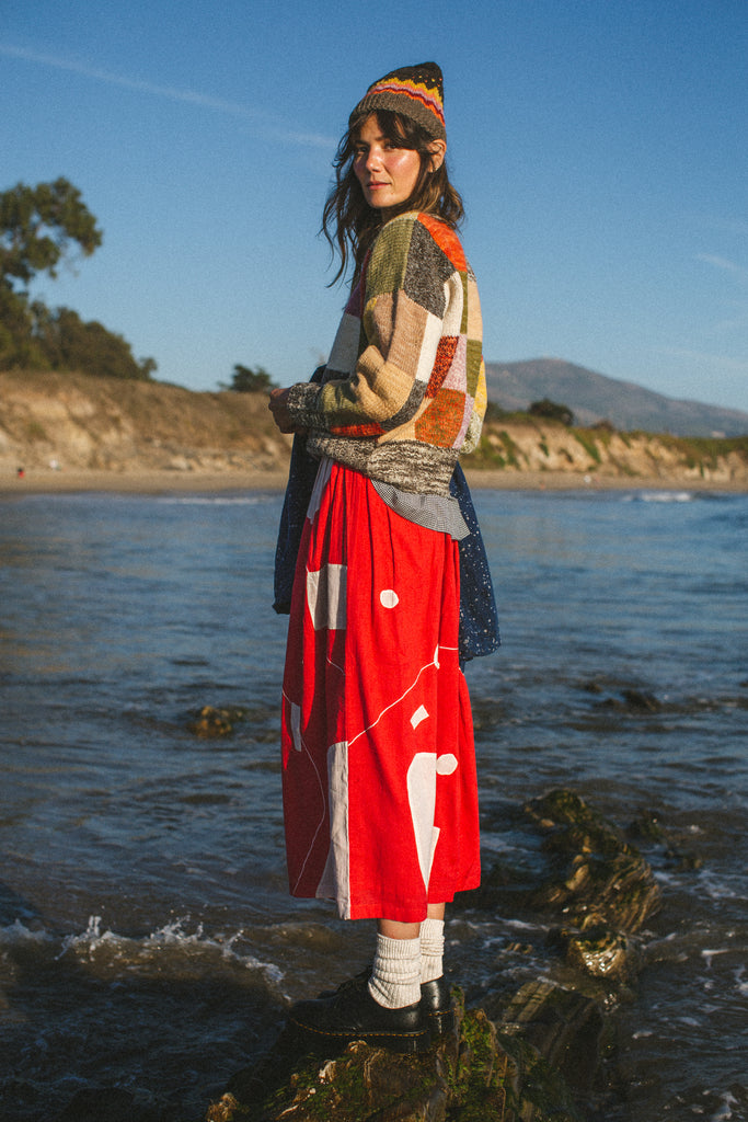 The Christmas Skirt, a vibrant red skirt features bold white patches and intricate appliqué needlework, combining comfort and style in a standout design