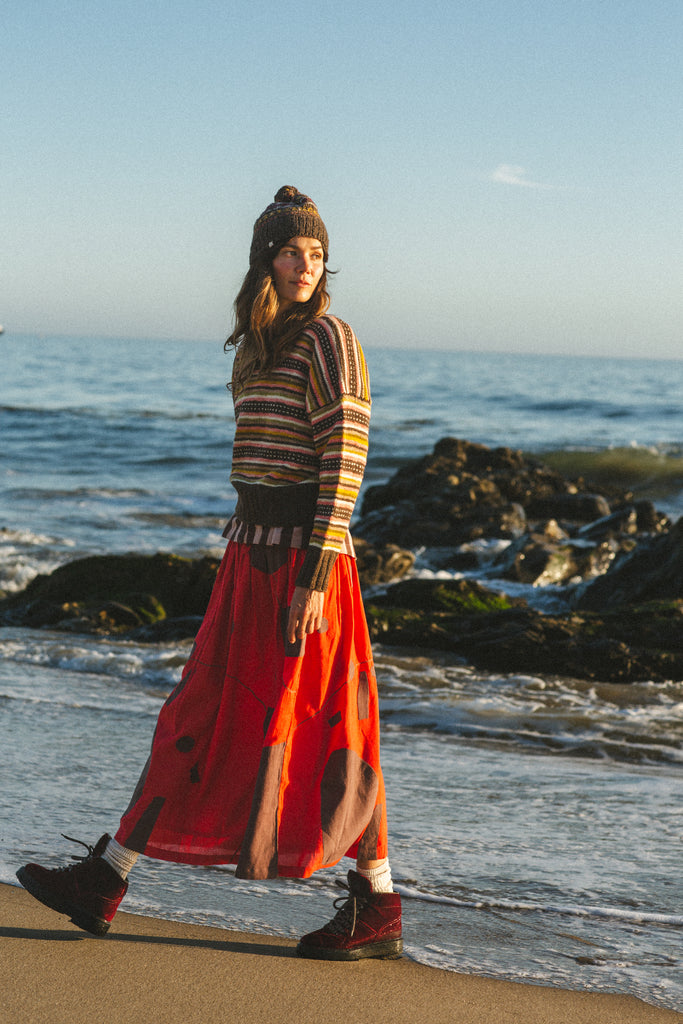 A bold red skirt with brown accents, showcasing unique appliqué craftsmanship and a versatile mid-calf length.