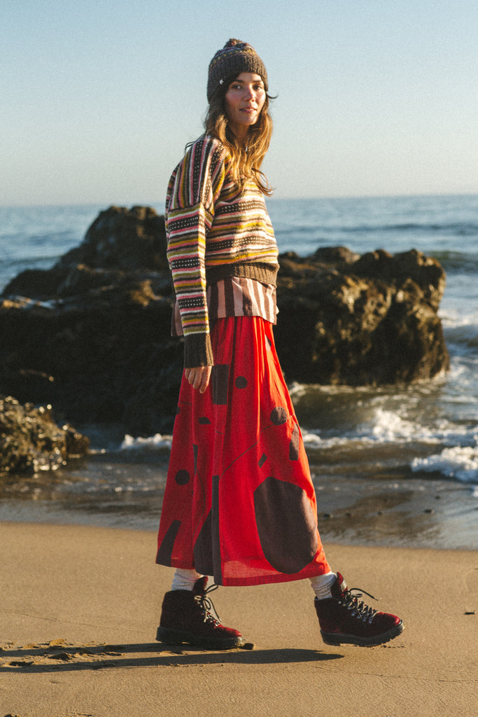 A bold red skirt with brown accents, showcasing unique appliqué craftsmanship and a versatile mid-calf length.