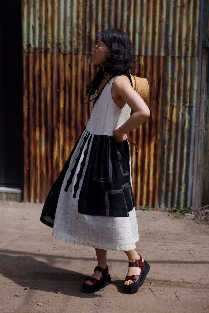 Introducing the Joan dress, a stunning piece in timeless black & white colour. Handwoven from cotton, it showcases intricate appliqué and patchwork detailing for a touch of artisanal charm. Featuring a flattering round V-neck and sleeveless design, this A-line dress offers both elegance and comfort. Complete with convenient side pockets and a midi-length silhouette, it's the epitome of effortless style for any occasion.
