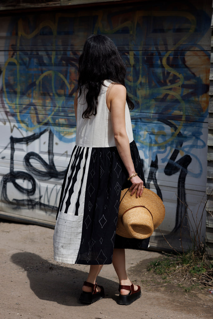 Introducing the Joan dress, a stunning piece in timeless black & white colour. Handwoven from cotton, it showcases intricate appliqué and patchwork detailing for a touch of artisanal charm. Featuring a flattering round V-neck and sleeveless design, this A-line dress offers both elegance and comfort. Complete with convenient side pockets and a midi-length silhouette, it's the epitome of effortless style for any occasion.