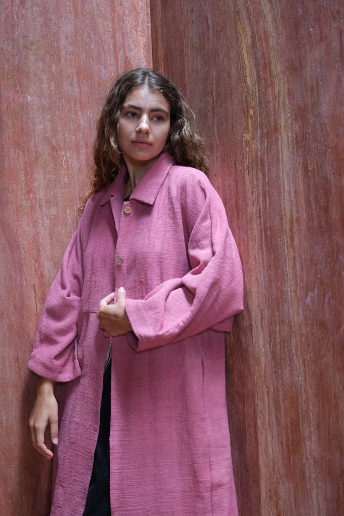 Introducing the Duster Jacket in a lovely pink shade, made from premium handwoven organic cotton in collaboration between Audrey E Leary and World of Crow. Featuring a straight collar, coconut buttons, and a relaxed fit with a straight hem, this versatile jacket offers a comfortable, midweight feel and fits true to size. Perfect for dressing up or adding sophistication to casual outfits.