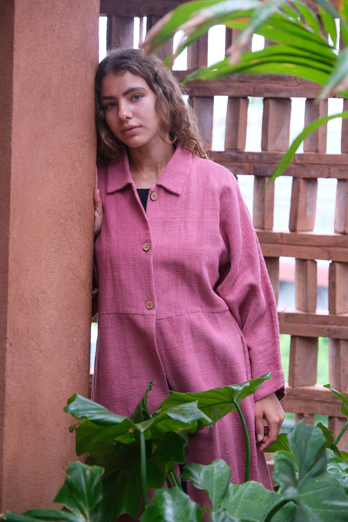 Introducing the Duster Jacket in a lovely pink shade, made from premium handwoven organic cotton in collaboration between Audrey E Leary and World of Crow. Featuring a straight collar, coconut buttons, and a relaxed fit with a straight hem, this versatile jacket offers a comfortable, midweight feel and fits true to size. Perfect for dressing up or adding sophistication to casual outfits.