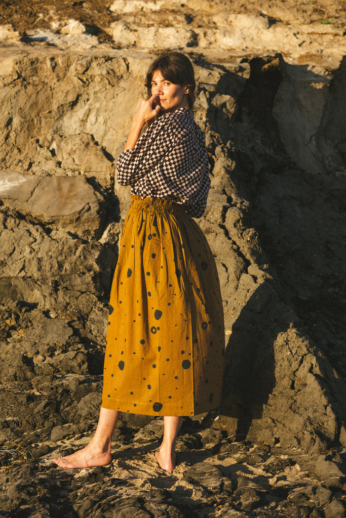 The Circles All Over Skirt features a striking brown and navy block print with circular patterns. Made from 100% handwoven cotton, it offers a comfortable mid-rise elasticated waistband and a chic mid-calf length, perfect for a polished yet relaxed style.