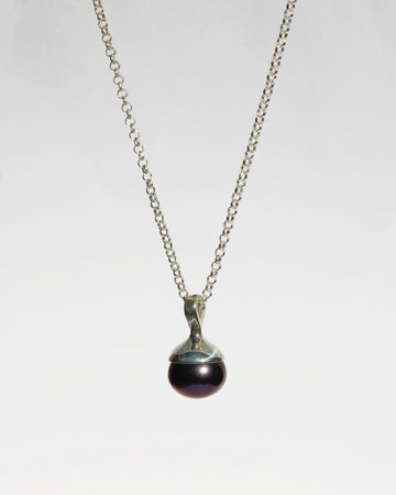 Introducing the sophisticated black pearl pendant, suspended on a classic sterling silver chain. This elegant piece features a lustrous black pearl that adds a touch of refinement to any ensemble. The pendant is available in both brass and sterling silver, and the chain is adjustable from 16" to 20" for a customizable fit.