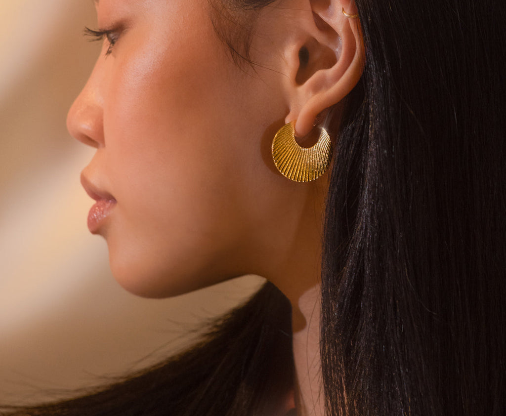 Introducing our vintage-inspired sunburst earrings in gold, featuring a scallop-shaped design that captures a timeless elegance. Handcrafted from brass with sterling silver posts, these earrings are available in both Small and Medium sizes. Elevate your look with these classic, radiant accessories.