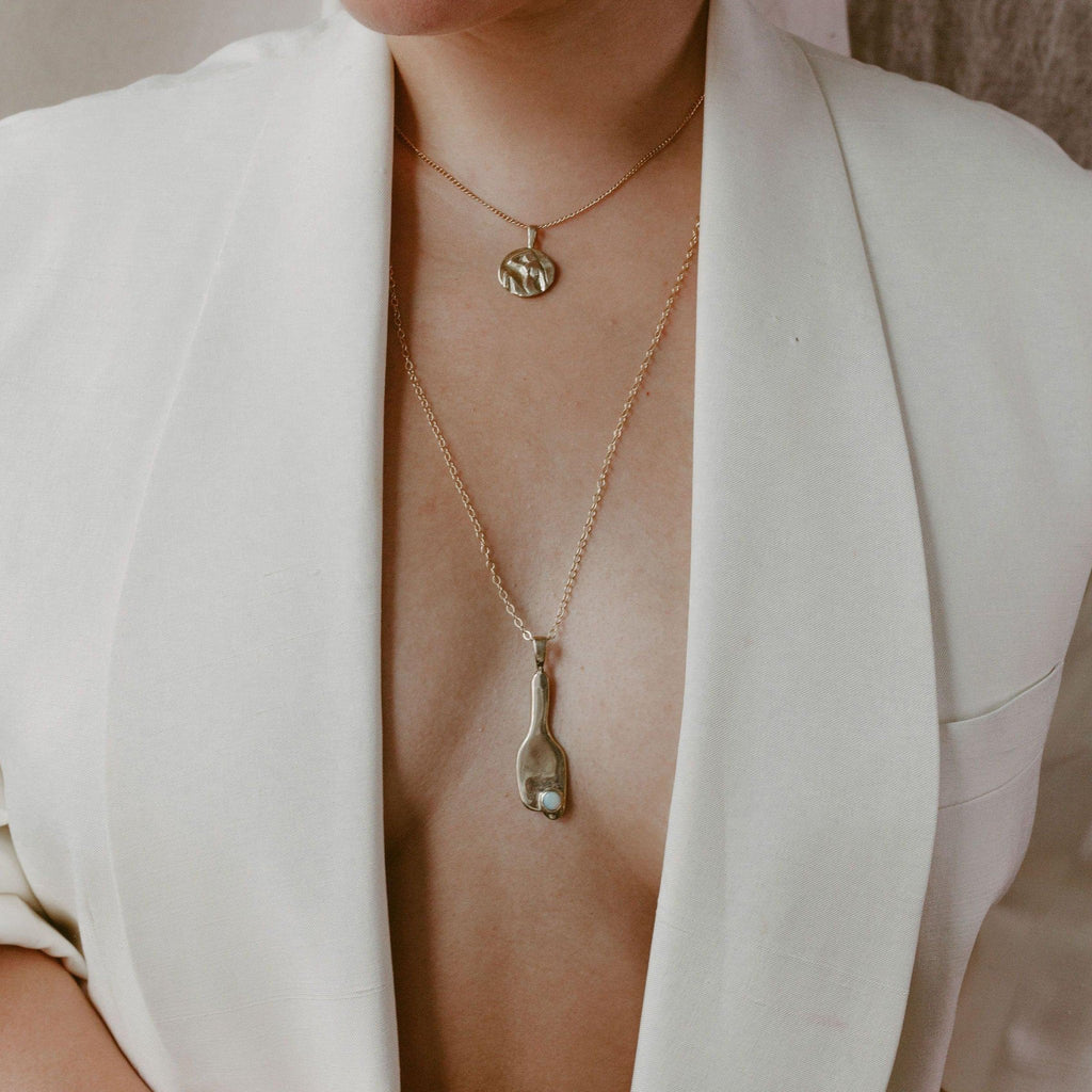 Introducing the Broken Vessel Necklace, a striking modernist design first carved in wax and cast in brass, then set with a 5mm Ethiopian Welo opal. This pendant hangs from a substantial 26" 14k gold fill chain, with the option for a customized length. Handmade in Southern California, this necklace symbolizes the beauty and light that shines through imperfections.