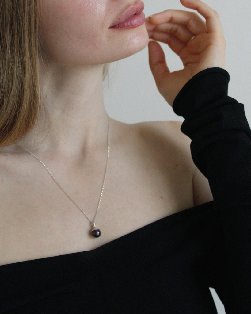 Introducing the sophisticated black pearl pendant, suspended on a classic sterling silver chain. This elegant piece features a lustrous black pearl that adds a touch of refinement to any ensemble. The pendant is available in both brass and sterling silver, and the chain is adjustable from 16" to 20" for a customizable fit.